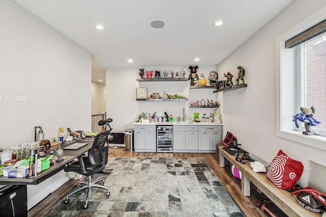 interior space featuring a dry bar, beverage cooler, a wealth of natural light, and wood finished floors