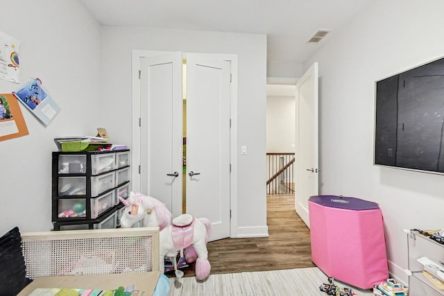 recreation room with visible vents, baseboards, and wood finished floors