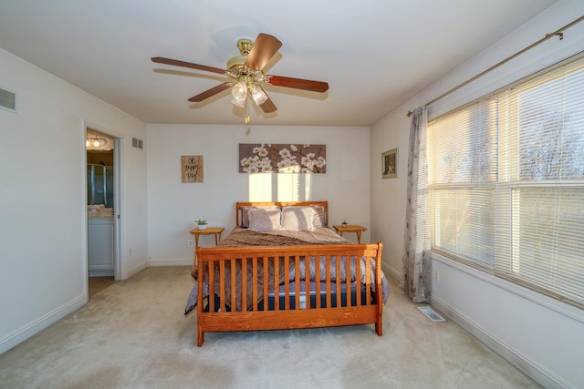 bedroom with ensuite bathroom, light carpet, and ceiling fan