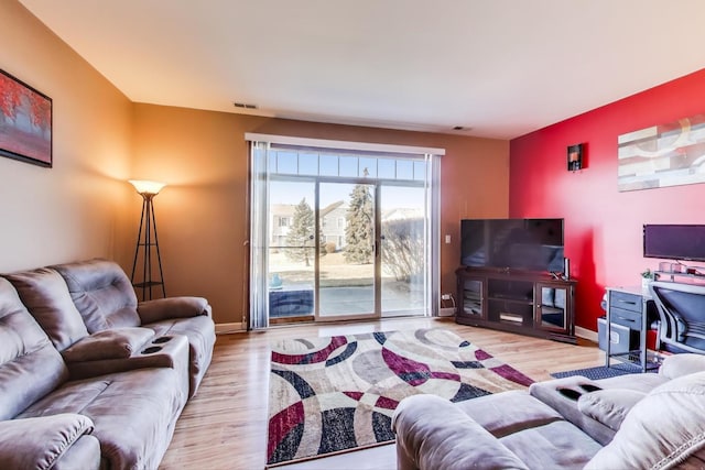 living area featuring baseboards, visible vents, and wood finished floors