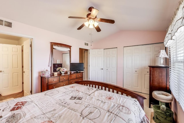 bedroom featuring lofted ceiling, a ceiling fan, visible vents, and multiple closets