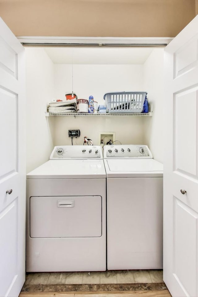 clothes washing area featuring laundry area, light wood finished floors, and washing machine and clothes dryer