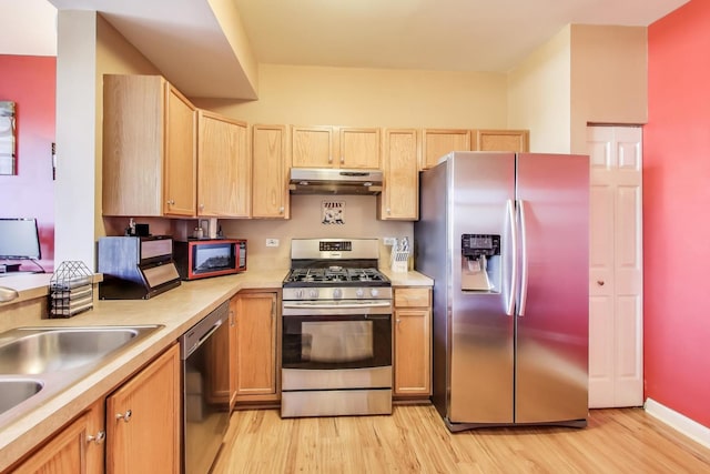 kitchen featuring under cabinet range hood, light wood-style flooring, stainless steel appliances, and light countertops