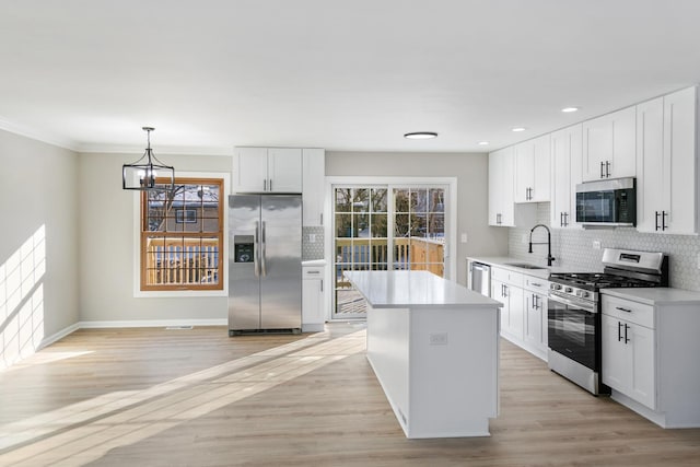 kitchen with sink, appliances with stainless steel finishes, white cabinetry, a center island, and decorative light fixtures