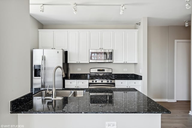 kitchen featuring sink, white cabinetry, dark stone countertops, stainless steel appliances, and hardwood / wood-style floors