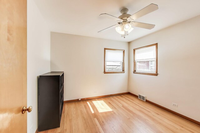 spare room with light wood-style floors, baseboards, visible vents, and ceiling fan