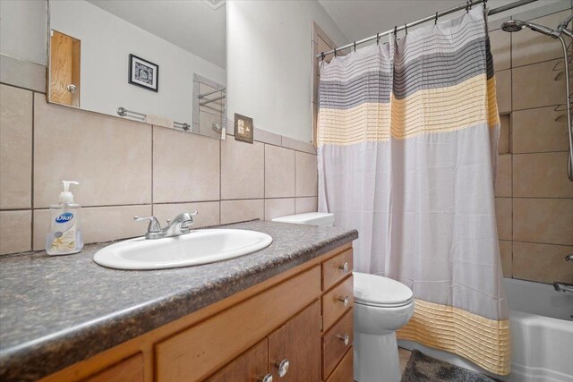 full bathroom with tile walls, backsplash, vanity, toilet, and shower / bath combo with shower curtain