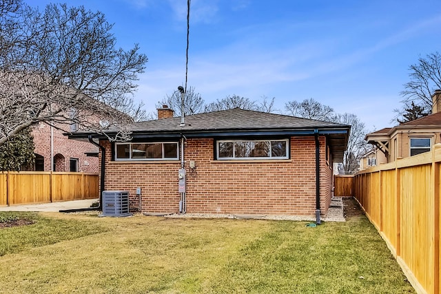 rear view of property featuring a yard and central air condition unit