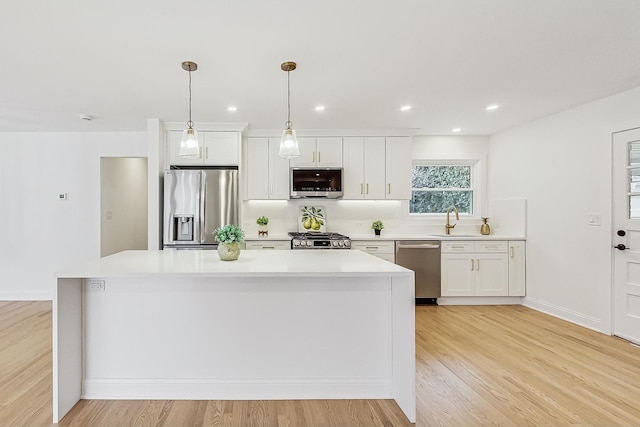 kitchen with white cabinetry, pendant lighting, a center island, and appliances with stainless steel finishes