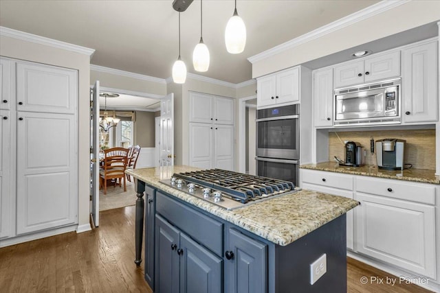 kitchen featuring light stone counters, blue cabinets, white cabinetry, appliances with stainless steel finishes, and a center island