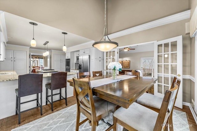 dining room featuring a ceiling fan, plenty of natural light, crown molding, and wood finished floors