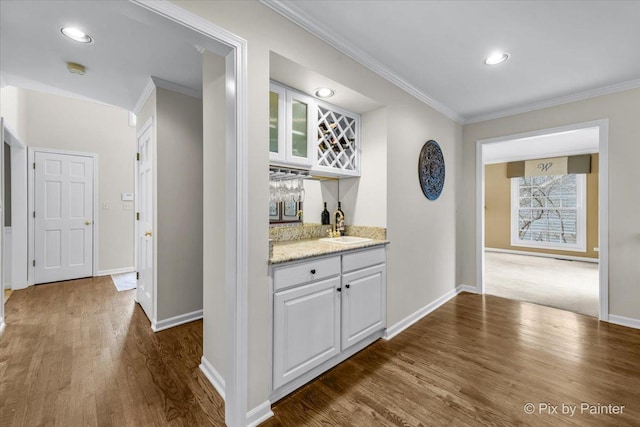 bar with dark wood-style floors, a dry bar, a sink, and crown molding