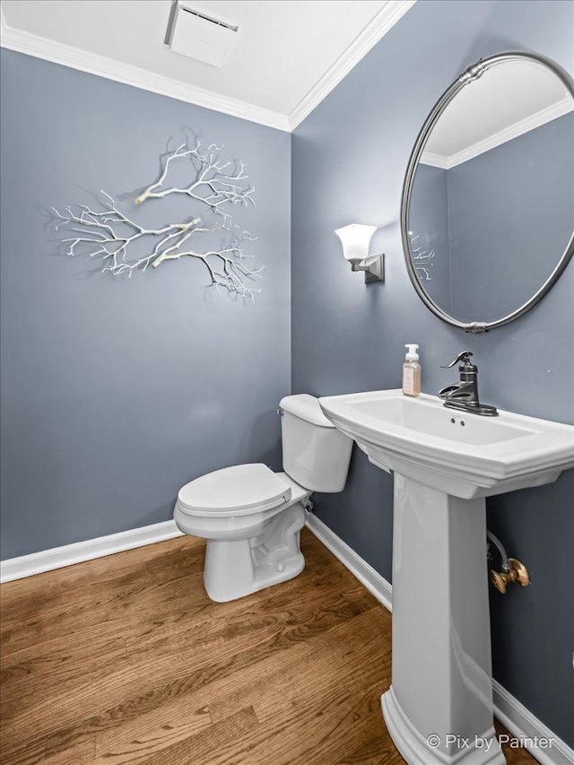 half bath featuring baseboards, wood finished floors, toilet, and crown molding