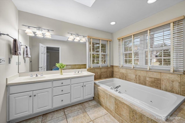 bathroom featuring double vanity, a jetted tub, a sink, and recessed lighting