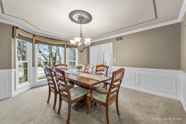 dining room with a chandelier, visible vents, crown molding, and light carpet