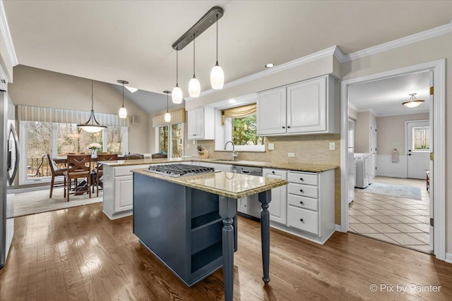 kitchen featuring a kitchen island, washing machine and clothes dryer, a peninsula, white cabinetry, and pendant lighting