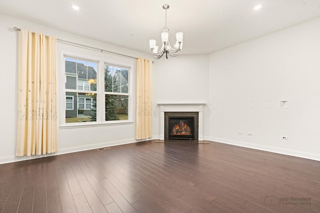 unfurnished living room with an inviting chandelier and dark hardwood / wood-style flooring