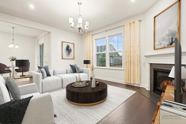 living room featuring a premium fireplace, dark wood-type flooring, and a chandelier