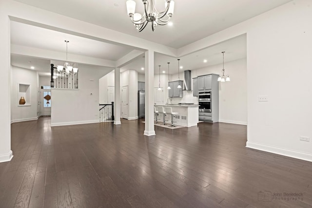 unfurnished living room featuring dark hardwood / wood-style flooring, a notable chandelier, and sink