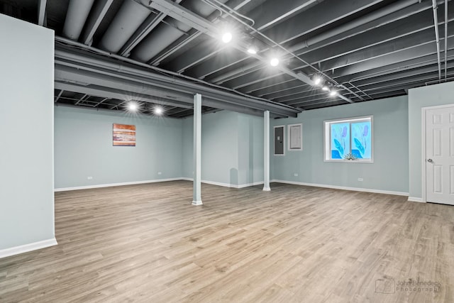 basement featuring hardwood / wood-style flooring and electric panel