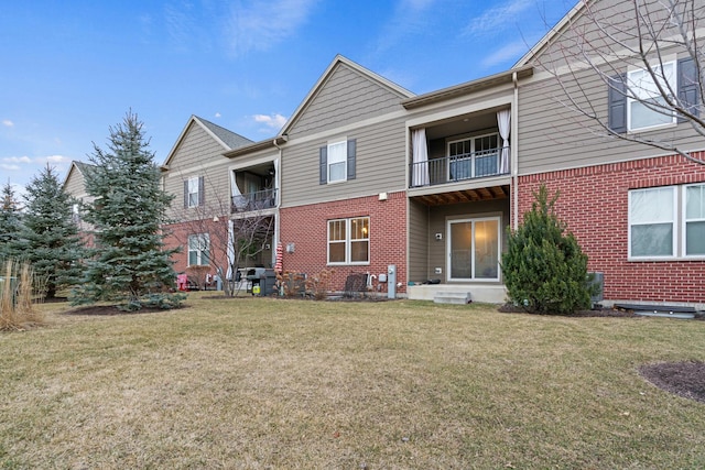 rear view of property featuring a balcony and a yard