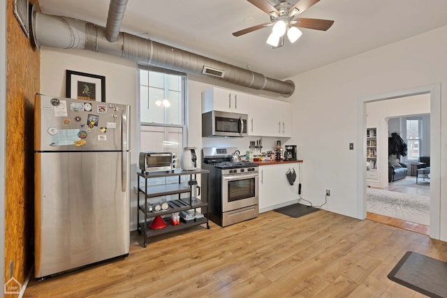 kitchen with ceiling fan, stainless steel appliances, light hardwood / wood-style floors, and white cabinets