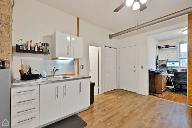 kitchen with sink, ceiling fan, white cabinets, and light wood-type flooring