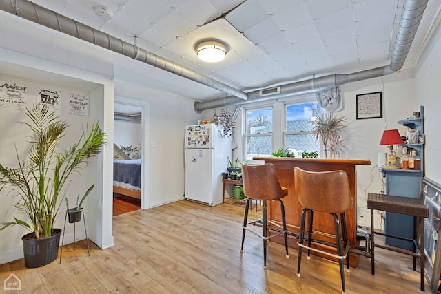 bar with hardwood / wood-style flooring and white fridge