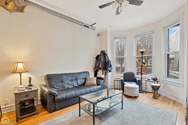 living room featuring hardwood / wood-style floors, crown molding, a wealth of natural light, and ceiling fan