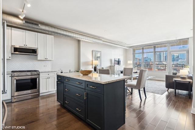 kitchen with tasteful backsplash, appliances with stainless steel finishes, dark hardwood / wood-style flooring, and white cabinets