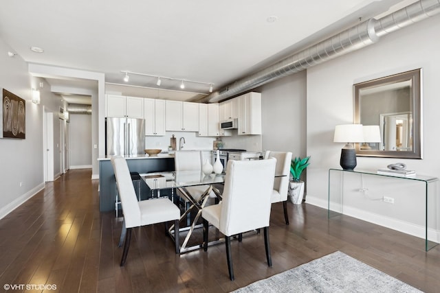 dining space featuring track lighting, dark hardwood / wood-style floors, and sink