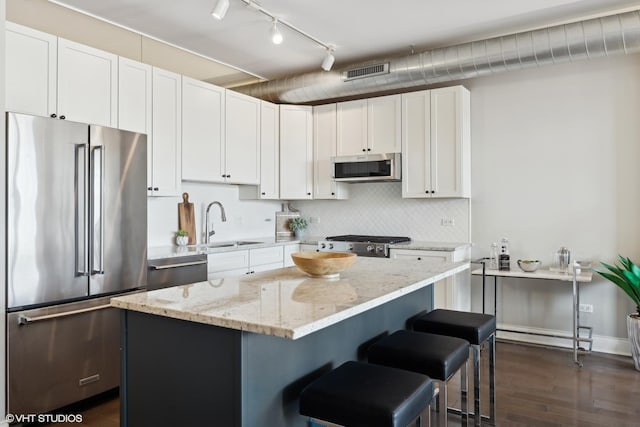 kitchen with white cabinetry, appliances with stainless steel finishes, a center island, and light stone counters