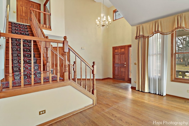 entryway with a notable chandelier, wood-type flooring, and a high ceiling