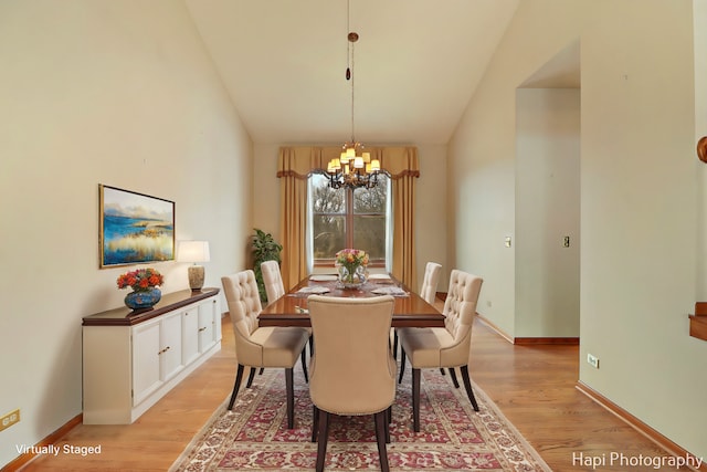 dining area with an inviting chandelier, lofted ceiling, and light hardwood / wood-style floors