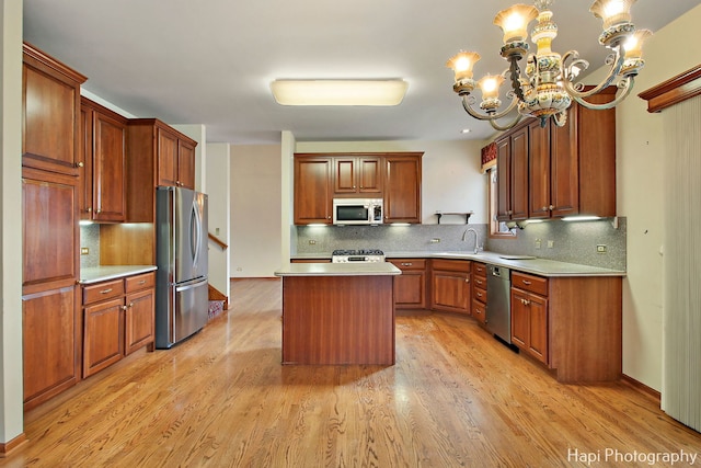 kitchen featuring tasteful backsplash, decorative light fixtures, a kitchen island, stainless steel appliances, and light hardwood / wood-style floors