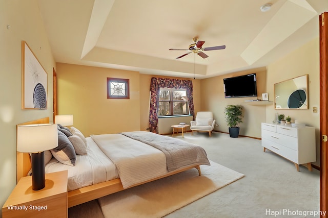 carpeted bedroom featuring a tray ceiling and ceiling fan