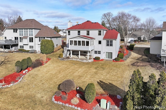 rear view of property featuring a yard and a sunroom