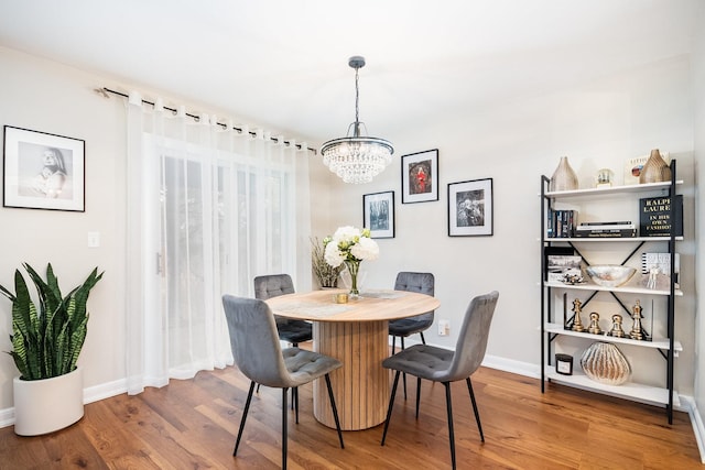 dining space with hardwood / wood-style floors and a notable chandelier