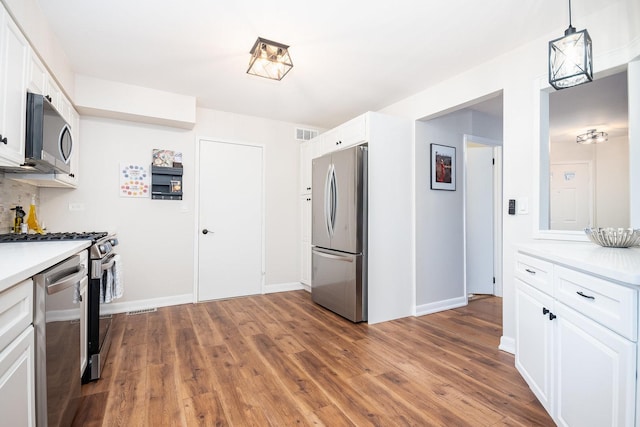 kitchen featuring hanging light fixtures, appliances with stainless steel finishes, and white cabinets