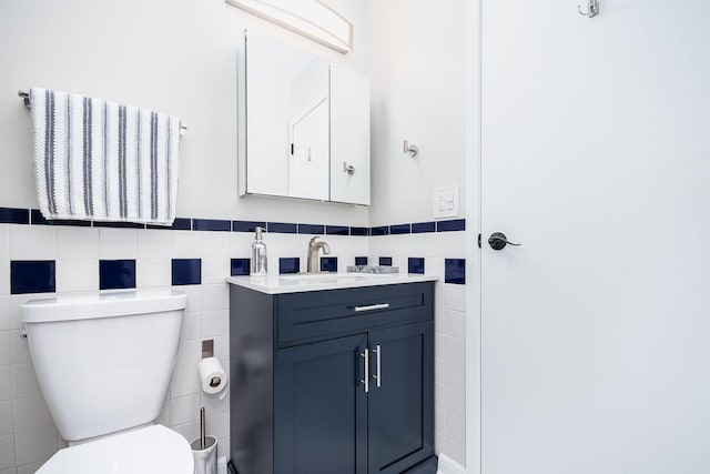 bathroom with vanity, toilet, and tile walls