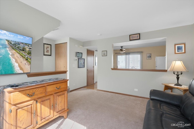 living area featuring ceiling fan, baseboards, and light carpet