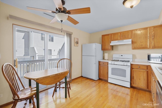 kitchen with under cabinet range hood, light wood-type flooring, white appliances, and light countertops