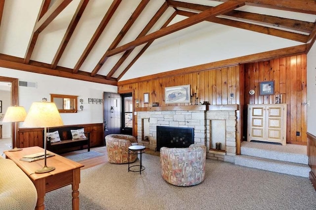 carpeted living room with beam ceiling, a stone fireplace, high vaulted ceiling, and wood walls