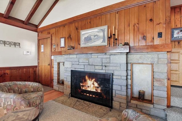 details featuring beamed ceiling, a stone fireplace, and wooden walls