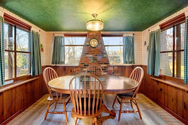 dining space with wooden walls, light hardwood / wood-style flooring, and a textured ceiling