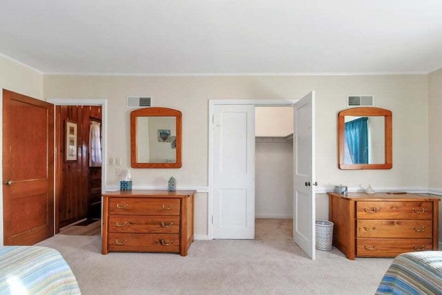 bedroom featuring ornamental molding, a spacious closet, light colored carpet, and a closet