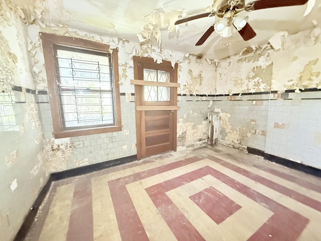 7243 S Perry Ave, Chicago, IL 60621 - unfurnished room with tile walls, inlaid floor details, ceiling fan, wainscoting, and wallpapered walls