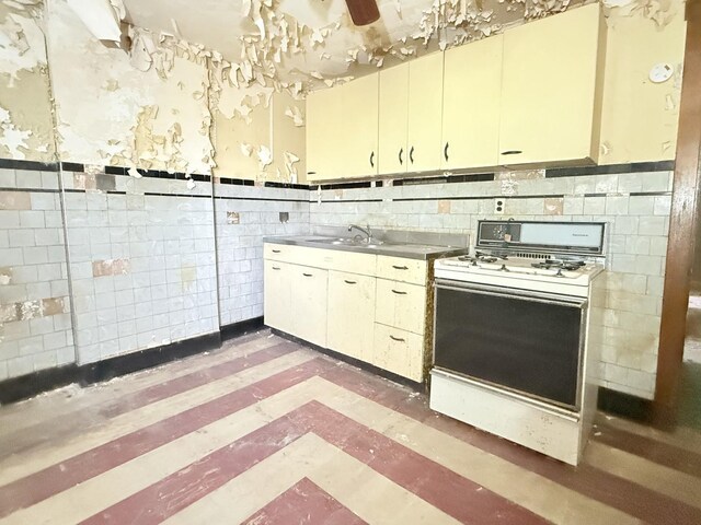 7243 S Perry Ave, Chicago, IL 60621 - kitchen with white gas stove, a sink, tile walls, and wainscoting