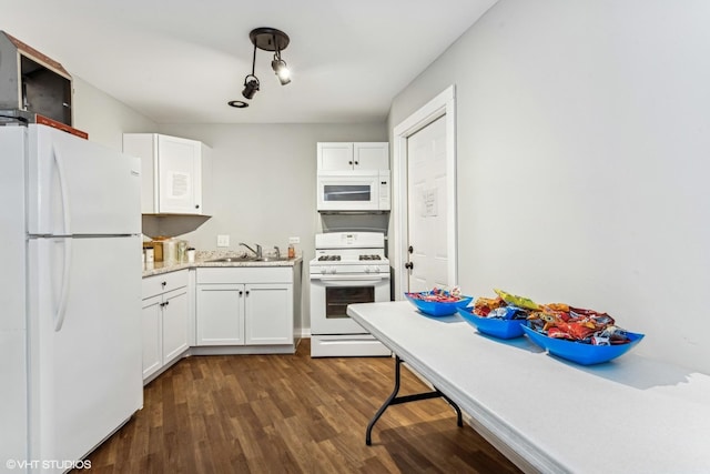 kitchen with white appliances, a sink, white cabinets, light stone countertops, and dark wood finished floors