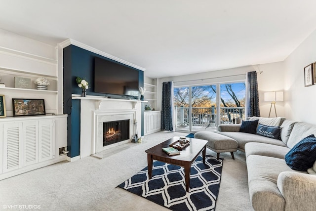 living area with a warm lit fireplace, built in shelves, and carpet flooring